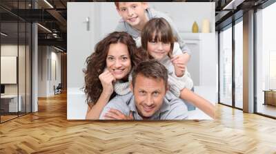 Happy family of 4 people laying on a sofa at home Wall mural