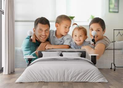 Happy family of four sitting on sofa Wall mural