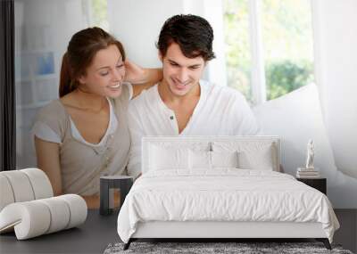 Happy young couple using laptop computer at home Wall mural