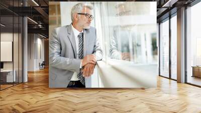 Mature businessman looking out window in modern office Wall mural