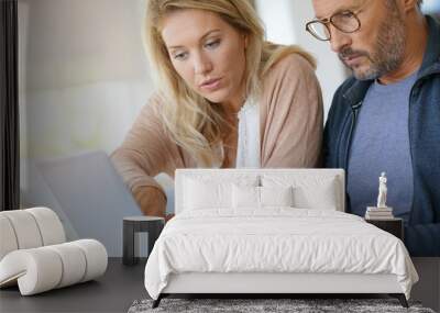 Mature couple at home working on laptop computer Wall mural