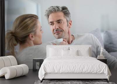 Mature couple talking together in sofa Wall mural