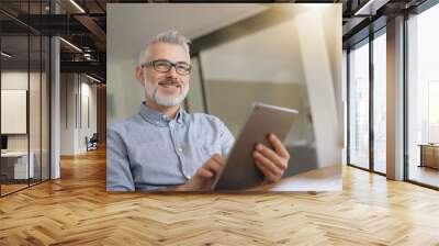 Mature man in office working with digital tablet Wall mural