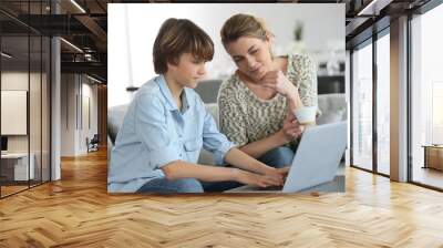 mother looking after son doing homework on laptop Wall mural