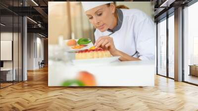 Pastry chef in professional kitchen decorating raspberry cake with fruits Wall mural