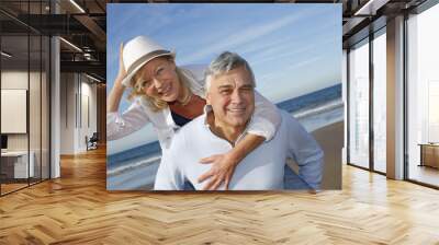 portrait of cheerful senior couple having fun at the beach Wall mural