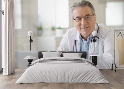 Portrait of senior doctor sitting in medical office Wall mural