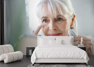 Portrait of senior woman applying anti-aging cream Wall mural