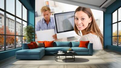 Portrait of smiling office worker in front of desktop Wall mural