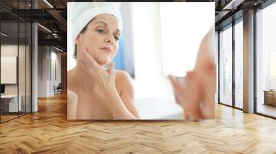 portrait of woman in bathroom applying moisturizing cream Wall mural