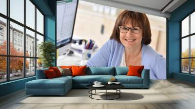 Senior woman in office in front of desktop Wall mural