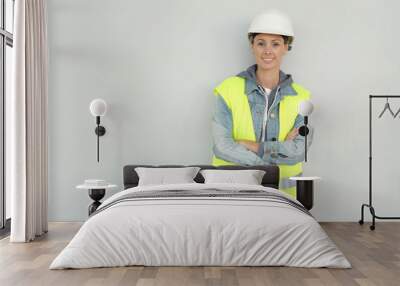 Smiling female construction worker in safety gear on grey background Wall mural