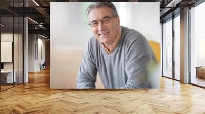 smiling senior man with eyeglasses relaxing in armchair Wall mural