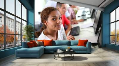 Smiling student girl sitting in computing class Wall mural