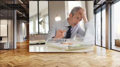 Stressed businessman working in contemporary office Wall mural