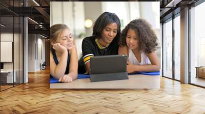 Woman with 2 young girls choosing virtual fitness class on internet Wall mural