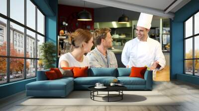 Young chef serving cooked dish to customers Wall mural