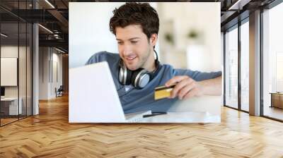 Young man buying music on internet with tablet Wall mural