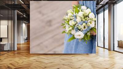 Closeup of a girl in a blue dress with a bouquet of white roses in her hands. A young woman is holding a beautiful wedding bouquet. Bride Wall mural