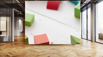 Closeup of colorful wooden toy blocks on white background wooden table. The child plays with colored cubes. Wall mural