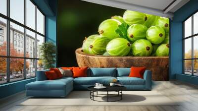 A pile of fresh gooseberries with their translucent green skins, some halved to reveal the juicy interior, arranged in a rustic wooden bowl Wall mural