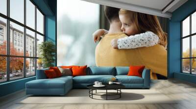 Affectionate little girl embracing her father while looking through the window Wall mural