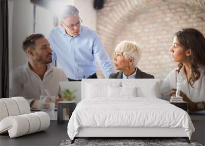 Team of business colleagues talking while working on a computer in the office Wall mural