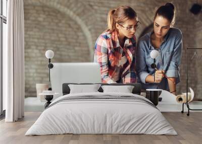 Two female architects discussing while working on new project in the office Wall mural