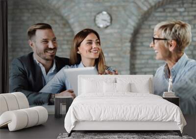 Young happy couple talking to their real estate agent on a business meeting in the office Wall mural