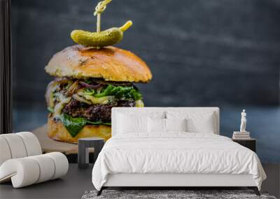 Tasty grilled beef burger with spinach lettuce and blue cheese served on wooden table with copyspace, blackboard in background. Wall mural