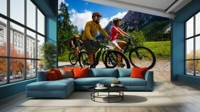 Tourist cycling in Cortina d'Ampezzo, stunning rocky mountains on the background. Family riding MTB enduro flow trail. South Tyrol province of Italy, Dolomites. Wall mural