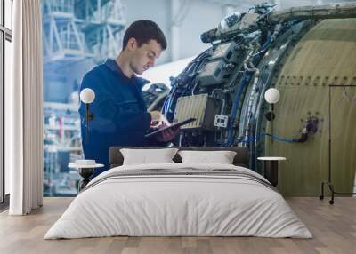 Aircraft Maintenance Mechanic Inspecting and Working on Airplane Jet Engine in Hangar Wall mural