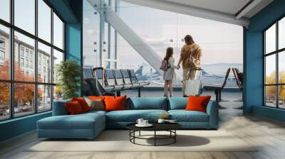 Airport Terminal: Beautiful Mother and Cute Little Daughter Wait for their Vacation Flight, Looking out of Window for Arriving and Departing Airplanes. Young Family in Boarding Lounge of Airline Hub Wall mural