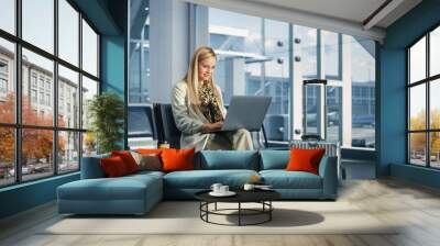 Airport Terminal: Smiling Woman Waits for Flight, Uses Laptop, Browse Internet, does e-Business, Online Shopping. Traveling Female Remote Work Online on Computer in a Boarding Lounge of Airline Hub Wall mural