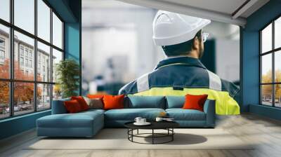 Back View Shot of the Industrial Engineer Wearing Protective Clothing Walks Through Modern Manufacturing Facility with Automatic Machinery Working in Background. Wall mural