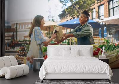 beautiful female customer buying sustainable organic vegetables from a joyful black female farmer on Wall mural