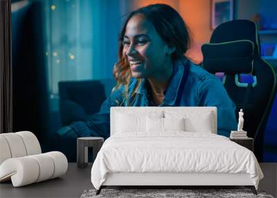 Beautiful Surprised and Excited Young Black Girl Watching Action Video on a Computer. She Has Dark Hair and Brown Eyes. Screen Adds Reflections to Her Face. Cozy Room is Lit with Warm Light. Wall mural