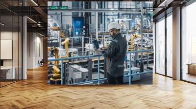 car factory engineer in work uniform using laptop computer. automotive industrial manufacturing faci Wall mural