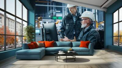 Car Factory Office: Female Manager Talks to Male Automotive Engineer Working on Computer. Automated Robot Arm Assembly Line Manufacturing Electric Vehicles. Technicians Monitoring Conveyor Production Wall mural