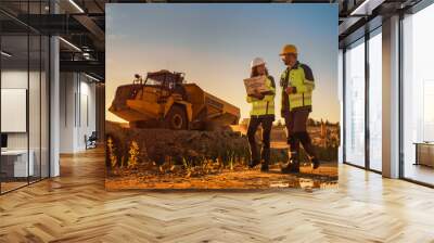 Caucasian Male Architect And Hispanic Female Urban Planner Walking On Construction Site With Laptop Computer And Talking About New Real Estate Project. Construction Truck Driving By. Golden Hour Wall mural