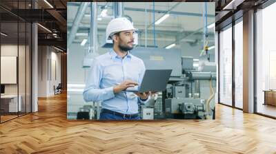 chief engineer in the hard hat walks through light modern factory while holding laptop. successful,  Wall mural