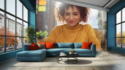 Close Up Portrait of a Happy Middle Eastern Manager Sitting at a Desk in Creative Office. Young Stylish Female with Curly Hair Using Laptop Computer in Marketing Agency. Wall mural