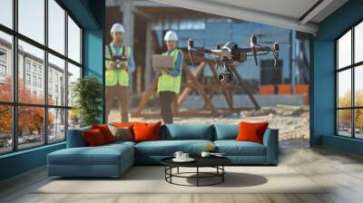 Diverse Team of Specialists Pilot Drone on Construction Site. Architectural Engineer and Safety Engineering Inspector Fly Drone on Commercial Building Construction Site Controlling Design and Quality Wall mural