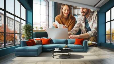 Doing Accounting at Home: Happy Couple Using Laptop Computer, Sitting on Sofa in Apartment. Young Family Filling Tax Forms, Mortgage Documents, Bills, Checks, Balances, Invoices are in Order Wall mural