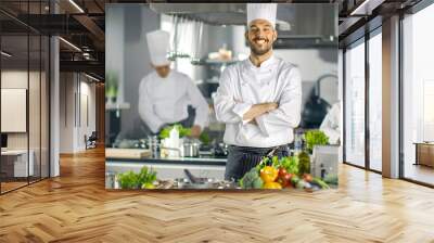 Famous Chef of a Big Restaurant Crosses Arms and Smiles in a Modern Kitchen. His Staff in Working in the Background. Wall mural