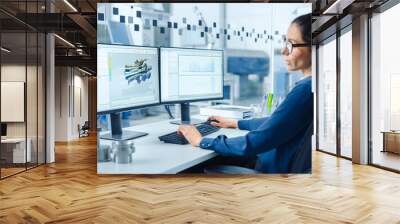 Female Industrial Engineer Solving Problems, Working on a Personal Computer, Two Monitor Screens Show CAD Software with 3D Prototype of Zero-Emissions Engine Being Tested. Working Modern Factory Wall mural