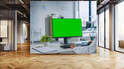 Female Medical Doctor is Working on a Computer with Green Screen Mock Up Display in a Health Clinic. Assistant in White Lab Coat is Reading Medical History Behind a Desk in Hospital Office.  Wall mural