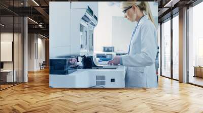 female research scientist putting test tubes with blood samples into analyzer medical machine. scien Wall mural