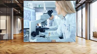 Female Research Scientist Using Electronic Microscope. She and Her Colleagues Work in a Big Modern Laboratory/ Medical Centre. Wall mural