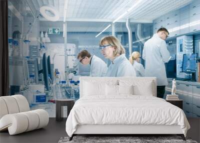 Female Scientist Analyzes Liquid in the Beaker and Types Down Observations on Her Computer. She's Working in a Busy Laboratory Full of Scientists Conducting Experiments. Wall mural